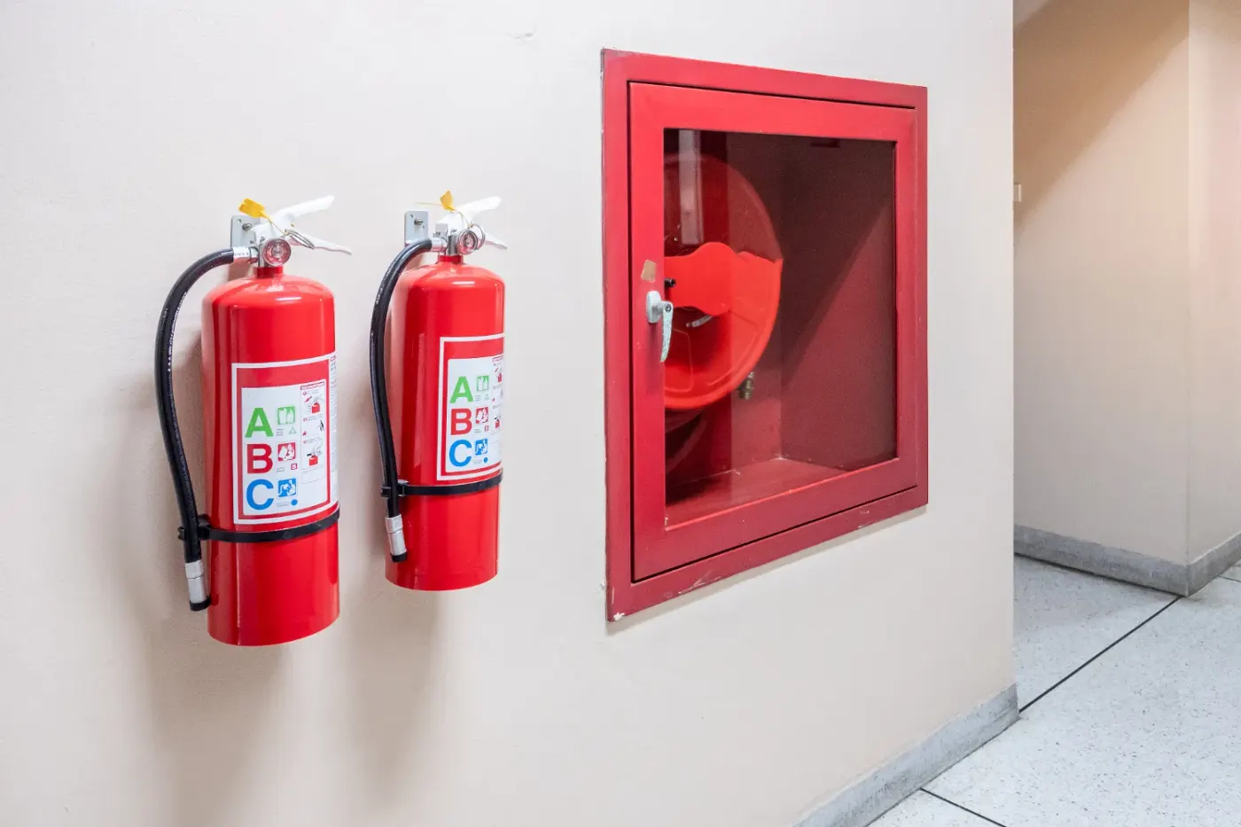 Extintores de incêndio e caixa de mangueira instalados em corredor de condomínio em Maringá